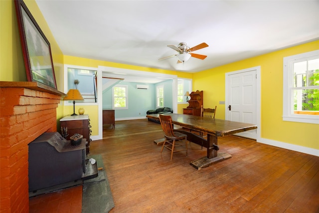 home office with baseboards, wood finished floors, a ceiling fan, and an AC wall unit