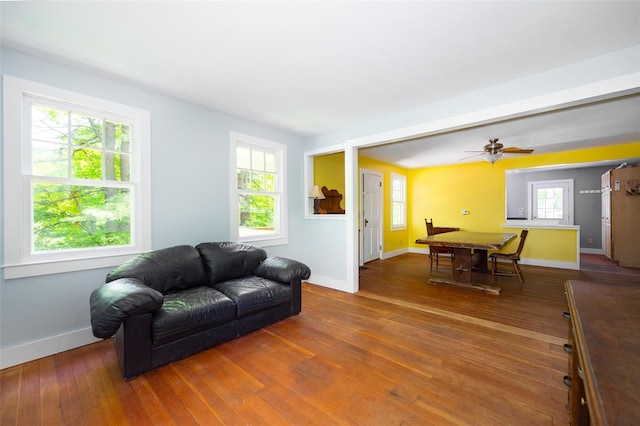 living area featuring healthy amount of natural light, hardwood / wood-style floors, baseboards, and ceiling fan