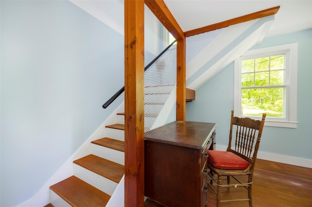 stairs with wood finished floors, baseboards, and vaulted ceiling
