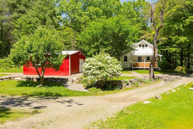 view of front facade with driveway, an outbuilding, and covered porch