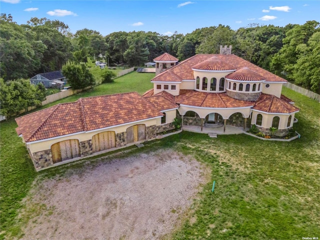 back of property with a tiled roof, driveway, stucco siding, an attached garage, and a chimney