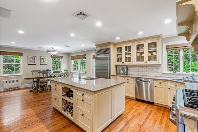 74 Eakins Rd, Manhasset, NY 11030 - kitchen featuring radiator, stainless steel appliances, cream cabinets, plenty of natural light, and crown molding