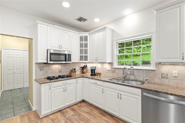 306 Mountain Rd, Pleasantville, NY 10570 - kitchen with appliances with stainless steel finishes, light stone counters, glass insert cabinets, white cabinetry, and decorative backsplash