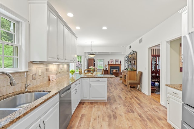 306 Mountain Rd, Pleasantville, NY 10570 - kitchen featuring stainless steel appliances, light wood-style flooring, a lit fireplace, a peninsula, and white cabinetry