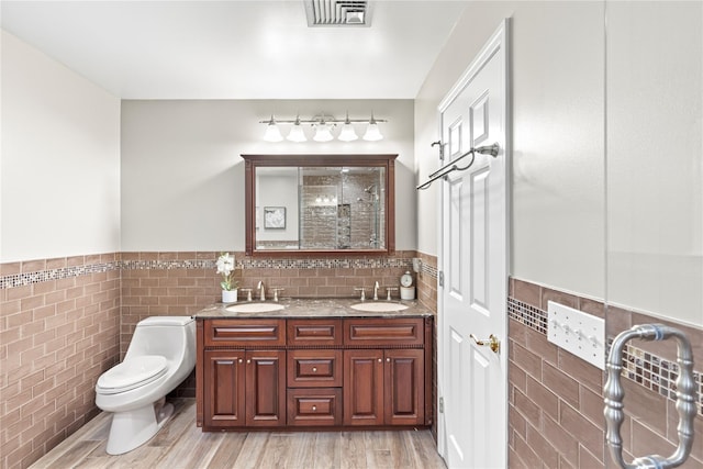 306 Mountain Rd, Pleasantville, NY 10570 - bathroom with tile walls, a wainscoted wall, a tile shower, double vanity, and wood finished floors