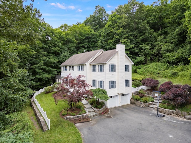 306 Mountain Rd, Pleasantville, NY 10570 - view of front of home featuring a chimney, asphalt driveway, a garage, a wooded view, and roof with shingles