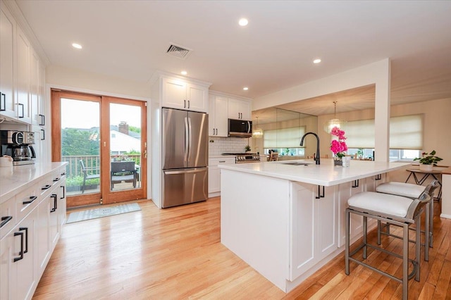 2083 Oliver Way, Merrick, NY 11566 - kitchen featuring appliances with stainless steel finishes, a sink, light wood finished floors, white cabinets, and healthy amount of natural light