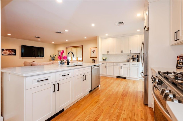 2083 Oliver Way, Merrick, NY 11566 - kitchen with a sink, stainless steel appliances, white cabinetry, light wood finished floors, and decorative backsplash