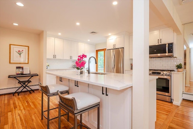 2083 Oliver Way, Merrick, NY 11566 - kitchen with stainless steel appliances, a sink, light wood-style flooring, backsplash, and recessed lighting