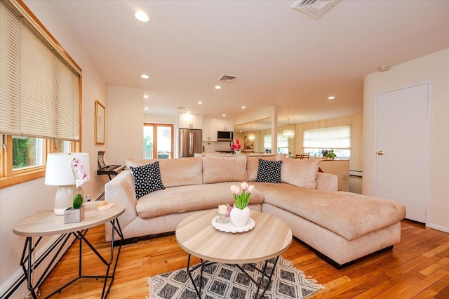 2083 Oliver Way, Merrick, NY 11566 - living area featuring baseboard heating, light wood finished floors, and recessed lighting
