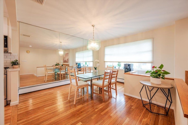 2083 Oliver Way, Merrick, NY 11566 - dining room featuring baseboard heating, healthy amount of natural light, light wood-type flooring, and a chandelier