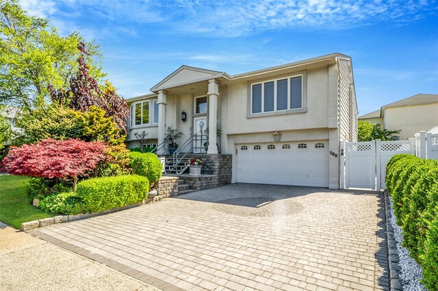 100 Mark Ln, Atlantic Beach, NY 11509 - split foyer home featuring stucco siding, a garage, a gate, and decorative driveway