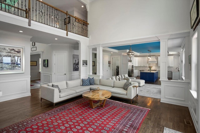 321 Sandpiper Dr, Riverhead, NY 11901 - living room featuring decorative columns, a high ceiling, dark wood finished floors, a decorative wall, and ornamental molding