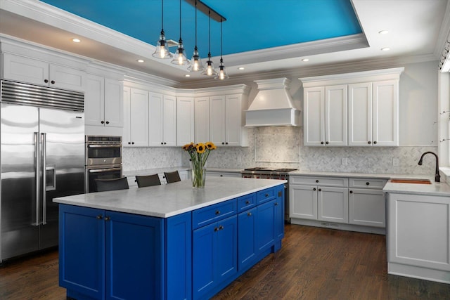 321 Sandpiper Dr, Riverhead, NY 11901 - kitchen with stainless steel appliances, custom range hood, blue cabinets, ornamental molding, and white cabinets