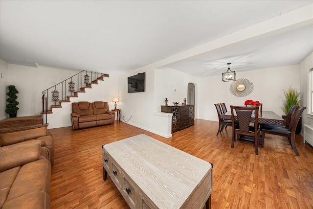 769 De Mott Ave, North Baldwin, NY 11510 - living room featuring light wood finished floors, a chandelier, stairs, and arched walkways