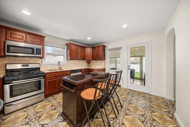769 De Mott Ave, North Baldwin, NY 11510 - kitchen featuring stainless steel appliances, a sink, arched walkways, tasteful backsplash, and a kitchen bar