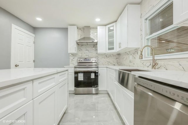 2600 Haff Ave, North Bellmore, NY 11710 - kitchen featuring wall chimney range hood, appliances with stainless steel finishes, light stone countertops, white cabinetry, and recessed lighting
