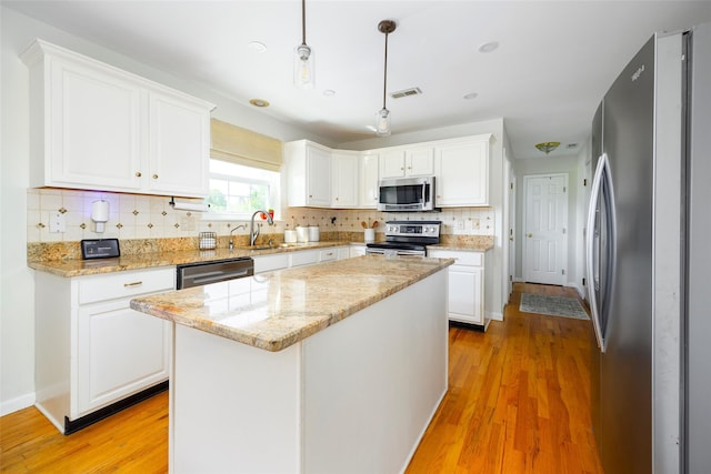 100 Meadow Ridge Ln, Lagrangeville, NY 12540 - kitchen with stainless steel appliances, white cabinetry, light wood-style flooring, decorative backsplash, and light stone countertops