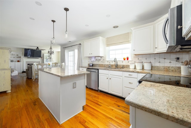 100 Meadow Ridge Ln, Lagrangeville, NY 12540 - kitchen featuring stainless steel appliances, a center island, white cabinetry, light wood-style flooring, and decorative light fixtures
