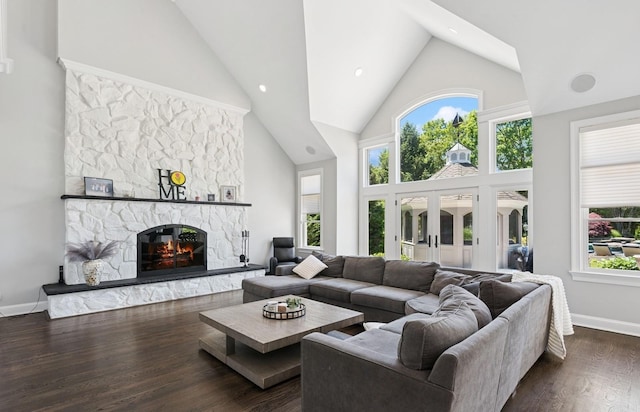 10 Colonial Dr, Smithtown, NY 11787 - living room with high vaulted ceiling, a stone fireplace, plenty of natural light, dark wood-type flooring, and baseboards