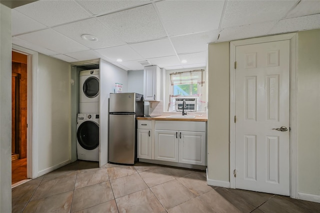 115 Dawn Rd, Rocky Point, NY 11778 - kitchen featuring freestanding refrigerator, stacked washing machine and dryer, a paneled ceiling, light tile patterned flooring, and white cabinets
