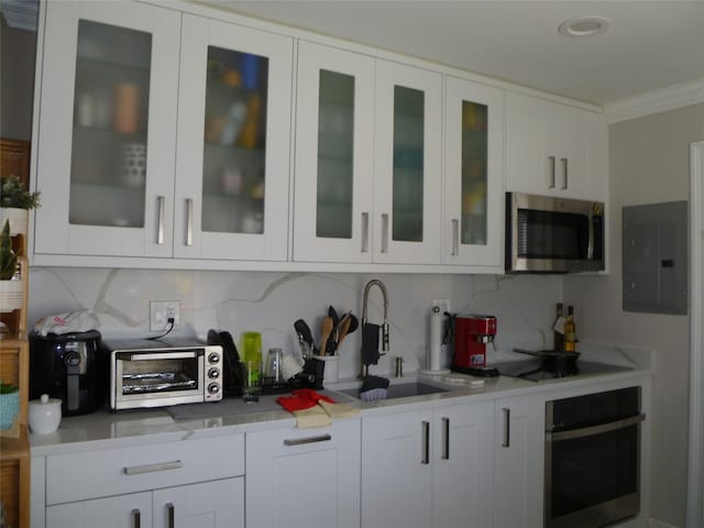 28 Crabtree Ln, Levittown, NY 11756 - kitchen with stainless steel appliances, decorative backsplash, electric panel, light countertops, and ornamental molding