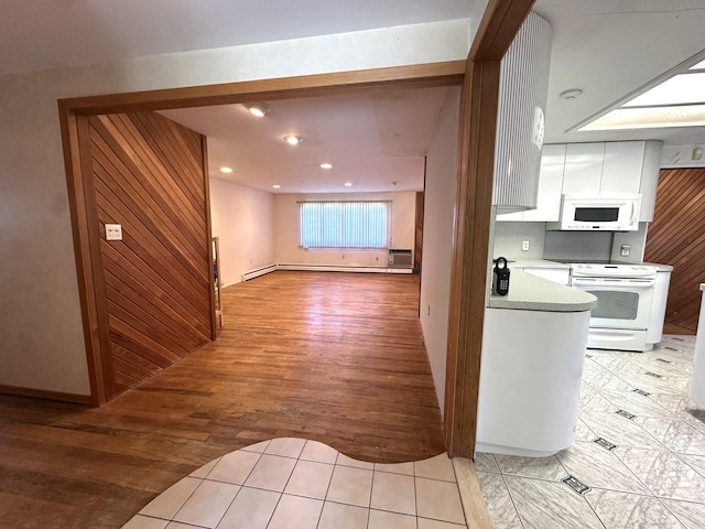 61 John St, Port Jefferson Station, NY 11776 - kitchen with white appliances, white cabinetry, light wood finished floors, light countertops, and baseboard heating