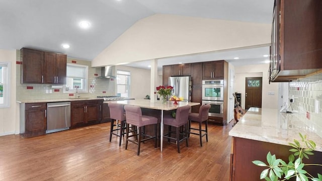 1434 Noel Ave, Hewlett, NY 11557 - kitchen featuring stainless steel appliances, wall chimney range hood, a sink, a breakfast bar area, and backsplash