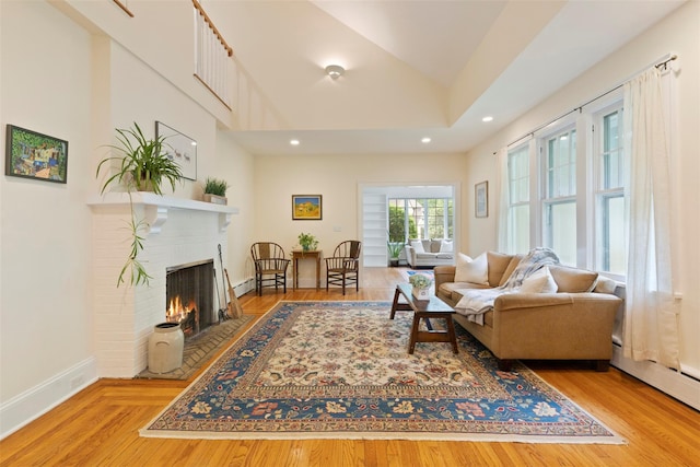 7 Ravine Dr, Hastings-On-Hudson, NY 10706 - living room with a brick fireplace, lofted ceiling, recessed lighting, wood finished floors, and baseboard heating