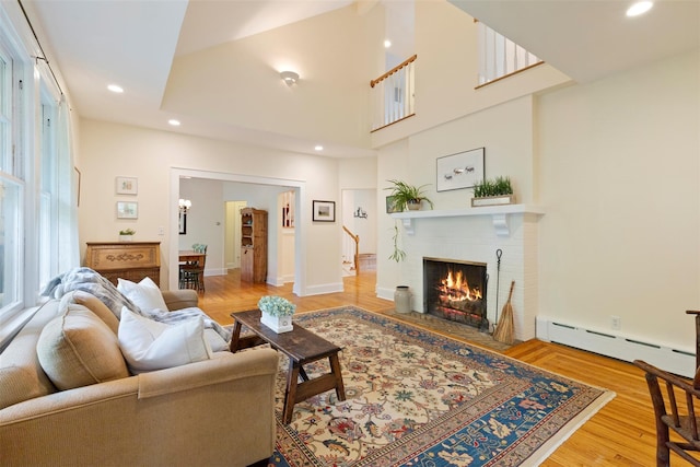 7 Ravine Dr, Hastings-On-Hudson, NY 10706 - living room with a baseboard heating unit, a fireplace, recessed lighting, a high ceiling, and wood finished floors