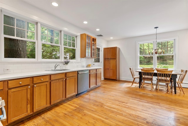 7 Ravine Dr, Hastings-On-Hudson, NY 10706 - kitchen with stainless steel dishwasher, a sink, brown cabinetry, light wood finished floors, and decorative backsplash