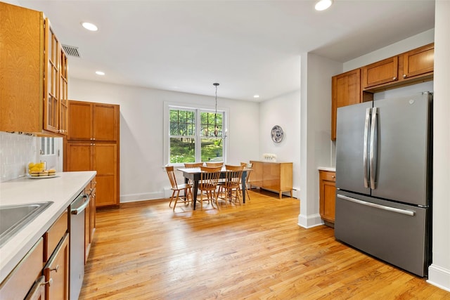 7 Ravine Dr, Hastings-On-Hudson, NY 10706 - kitchen featuring appliances with stainless steel finishes, brown cabinetry, light countertops, light wood-style floors, and recessed lighting