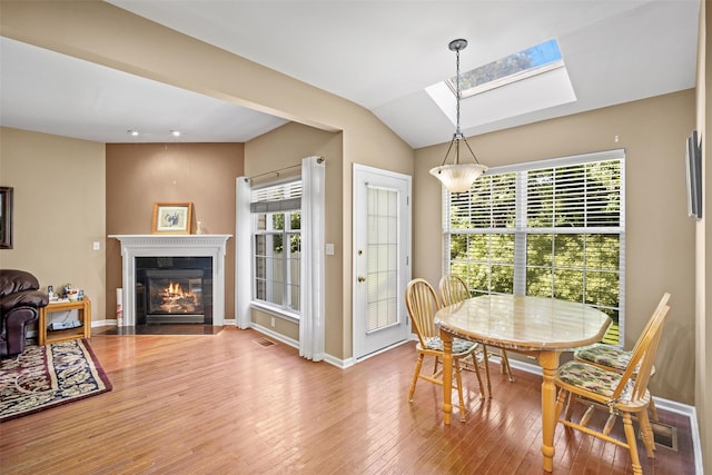 837 Huntington Dr Unit 152, Fishkill, NY 12524 - dining room featuring wood finished floors, a skylight, a glass covered fireplace, baseboards, and vaulted ceiling