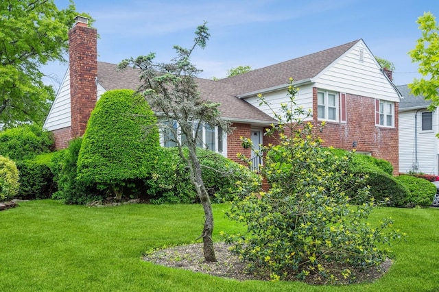 409 Jordan St, Oceanside, NY 11572 - view of front of property with a chimney, a front yard, brick siding, and a shingled roof
