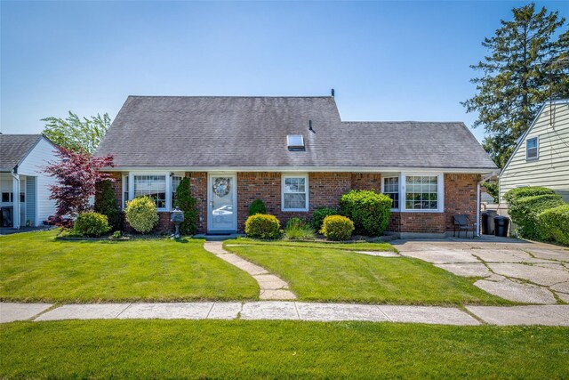 98 Bluespruce Rd, Levittown, NY 11756 - cape cod-style house with brick siding, a front lawn, and a shingled roof