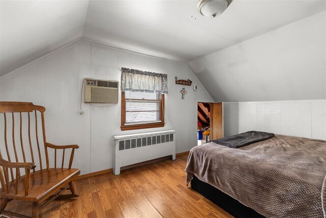 98 Bluespruce Rd, Levittown, NY 11756 - bedroom featuring radiator heating unit, lofted ceiling, light wood-style flooring, a wall unit AC, and baseboards