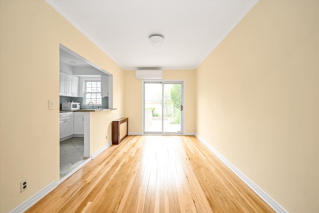 21-22 150th St, Whitestone, NY 11357 - unfurnished living room with a wall unit AC, light wood-type flooring, baseboards, and a sink
