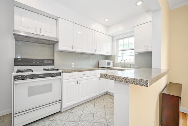 21-22 150th St, Whitestone, NY 11357 - kitchen with white appliances, under cabinet range hood, a sink, white cabinets, and a peninsula
