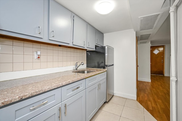 21-22 150th St, Whitestone, NY 11357 - kitchen with a sink, freestanding refrigerator, light tile patterned floors, decorative backsplash, and baseboards