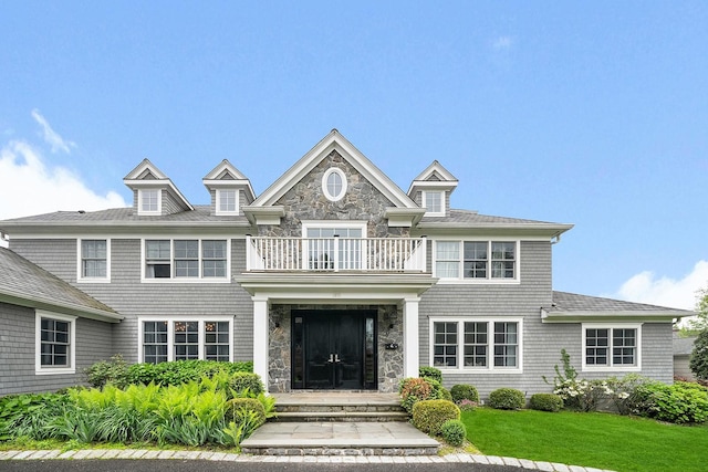 1015 Seven Oaks Ln, Mamaroneck, NY 10543 - shingle-style home with a balcony, a front lawn, and stone siding