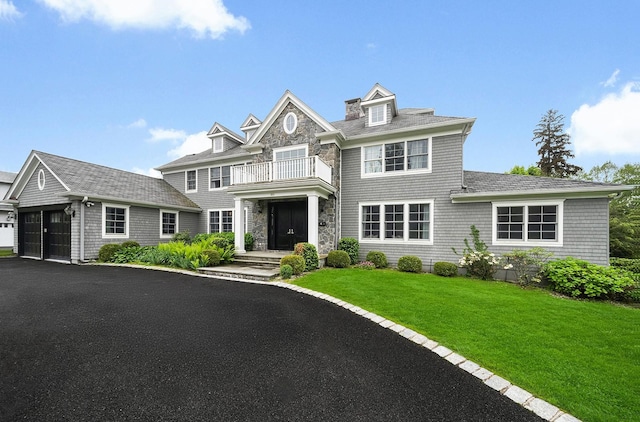 1015 Seven Oaks Ln, Mamaroneck, NY 10543 - shingle-style home featuring a balcony, an attached garage, driveway, a front lawn, and stone siding