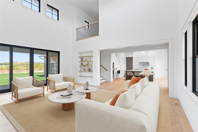 35 Club Dr, Baiting Hollow, NY 11933 - living area featuring a towering ceiling, light wood-style floors, stairs, and built in features
