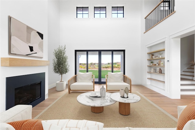 35 Club Dr, Baiting Hollow, NY 11933 - living area with built in features, a towering ceiling, wood finished floors, plenty of natural light, and a glass covered fireplace