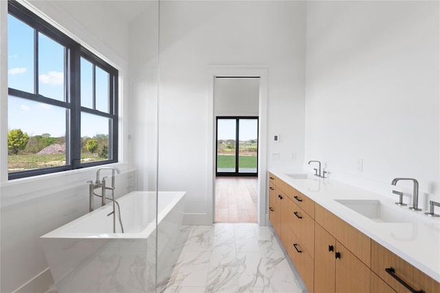 35 Club Dr, Baiting Hollow, NY 11933 - full bathroom with marble look tiles, a freestanding tub, double vanity, and baseboards