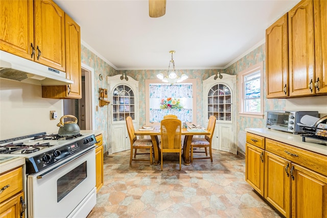 kitchen featuring white range with gas cooktop, wallpapered walls, under cabinet range hood, light countertops, and light stone finish flooring