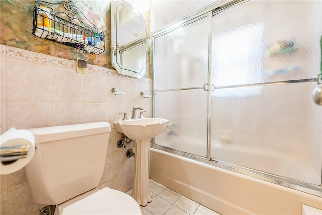 full bath with tile walls, toilet, bath / shower combo with glass door, and tile patterned flooring