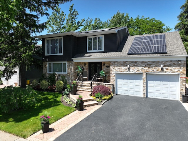 1010 S End, Woodmere, NY 11598 - view of front of property with an attached garage, driveway, solar panels, stone siding, and a front lawn