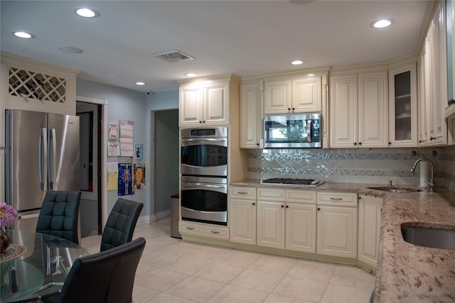 1010 S End, Woodmere, NY 11598 - kitchen featuring stainless steel appliances, cream cabinetry, light stone counters, decorative backsplash, and baseboards