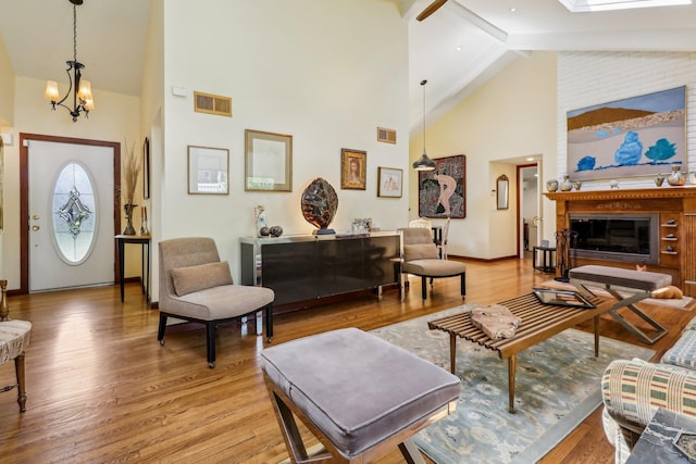 1 Meadowood Path, New Rochelle, NY 10804 - living area with high vaulted ceiling, a chandelier, light wood finished floors, a glass covered fireplace, and baseboards