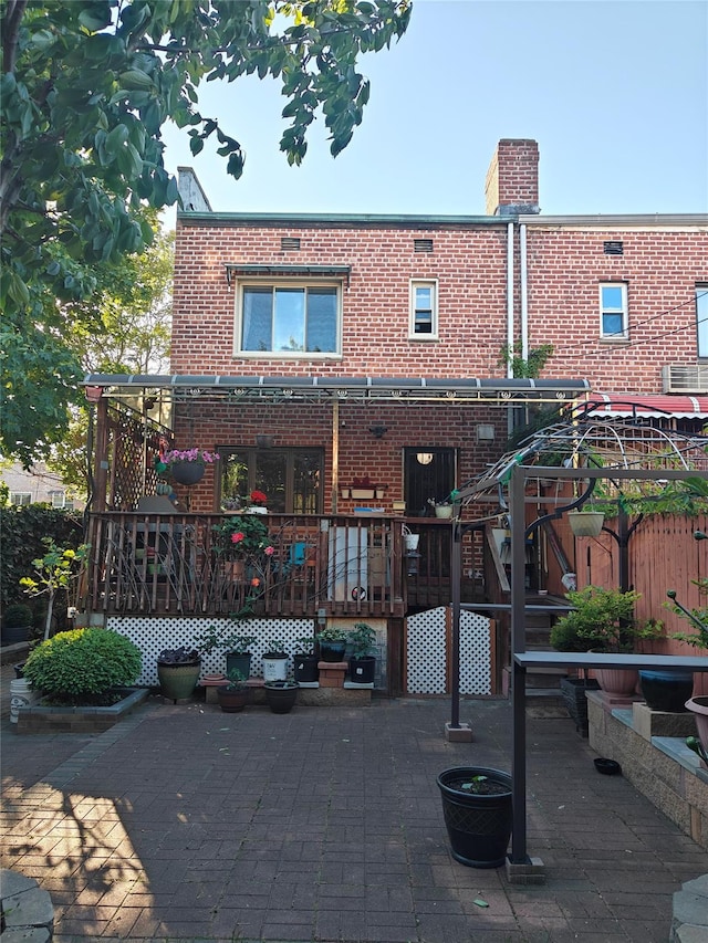 17-12 Starr St, Ridgewood, NY 11385 - rear view of house featuring a deck, brick siding, a patio area, and a chimney